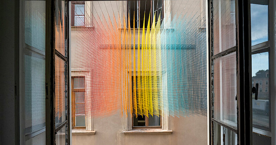 Blick aus Fenster auf mehrfarbiges Kunstinstallationsgeflecht